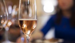 Une jeune femme boit une coupe de champagne durant un repas.