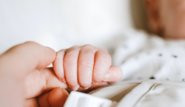 Un nourrisson tenant la main d'un adulte